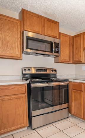 A kitchen with a refrigerator, cabinets, and a window.