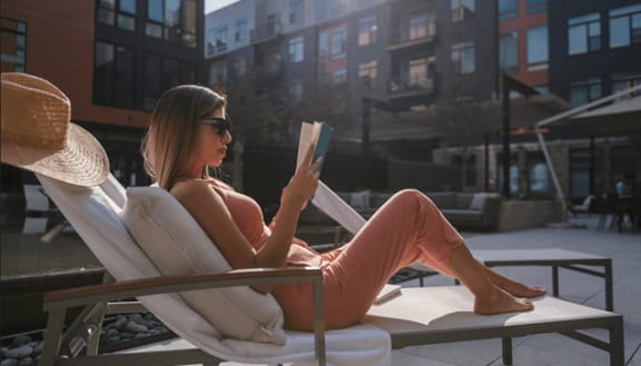 a woman sitting in a chair reading a bookat Arrowwood Apartments in North Bethesda, MD