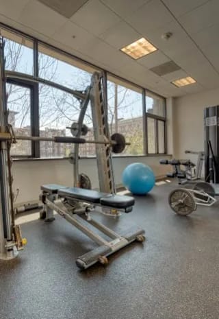 a workout room with weights and other exercise equipment in a building with windows