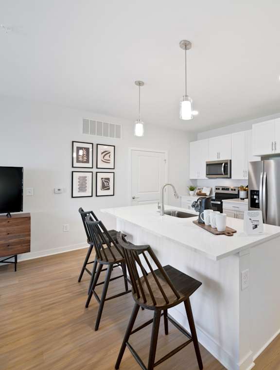 A kitchen with a white island and wooden chairs.