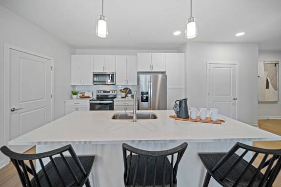 A modern kitchen with a white table and black chairs.