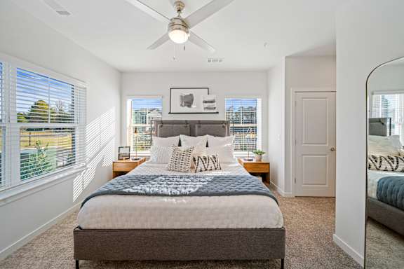 A bedroom with a large bed and a ceiling fan.