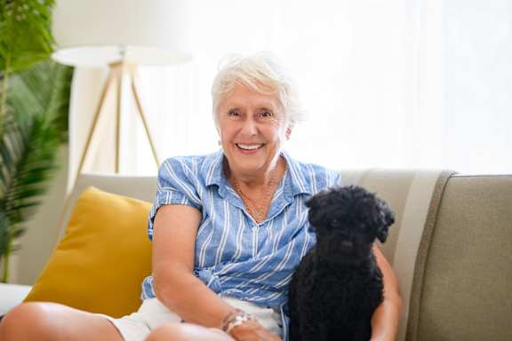 An elderly woman holding a small white dog.