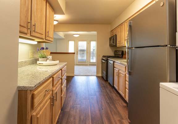 A kitchen with wooden cabinets and a stainless steel refrigerator.