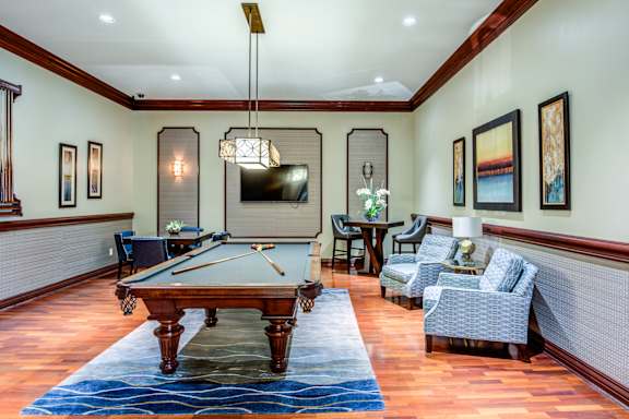 A pool table is in the middle of a room with a blue rug on the floor.