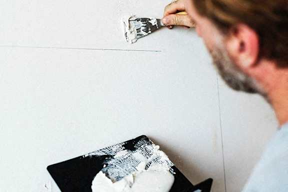 a man is scraping a wall with a paintbrush