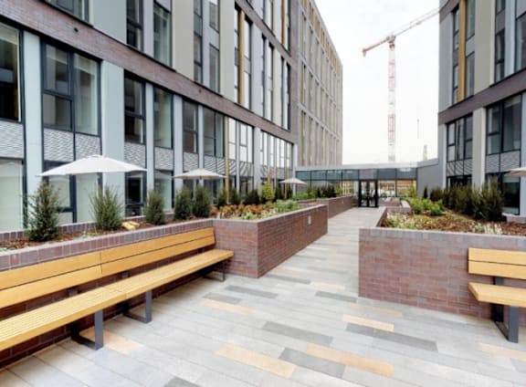 a courtyard with benches and plants in front of a building at The Trilogy Apartments, Manchester, M15 4RU