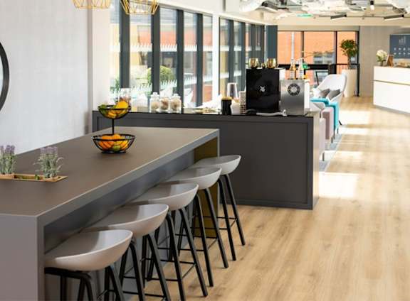A modern bar area with a long counter and stools. at The Trilogy Apartments, Manchester, M15 4RU