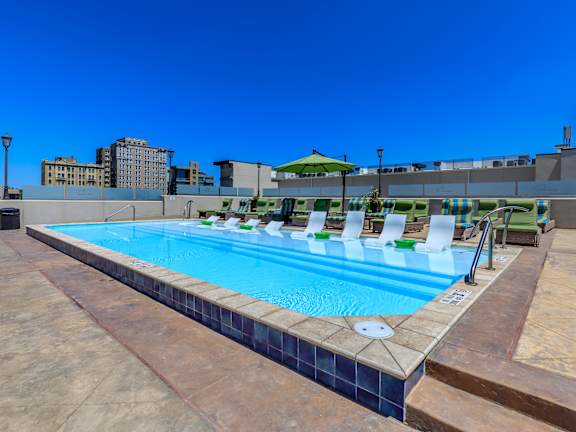 a swimming pool with lounge chairs and umbrellas on top of a building
