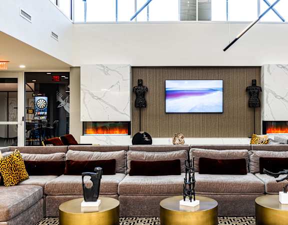 a living room with a large couch and a television on the wall  at The Grand, Kansas City, MO, 64106