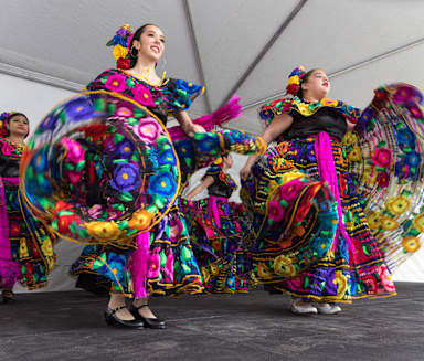 a group of women in colorful costumes dancing at a festival