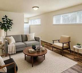 A living room with a grey couch, a brown armchair, a coffee table, and a potted plant.
