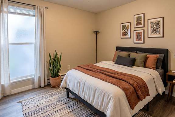 A bedroom with a large bed and a potted plant.
