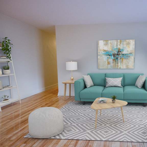 A living room with a teal couch, a grey armchair, a white pouf, a wooden coffee table, and a painting on the wall.
