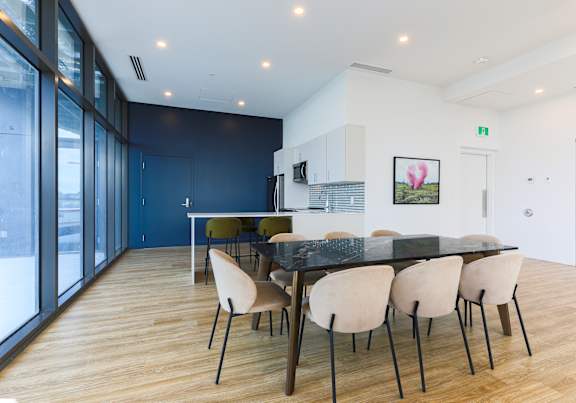 A modern dining room with a black table and white chairs.