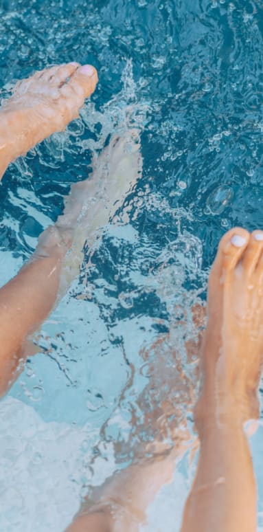 a pair of feet in a pool with water splashing around them