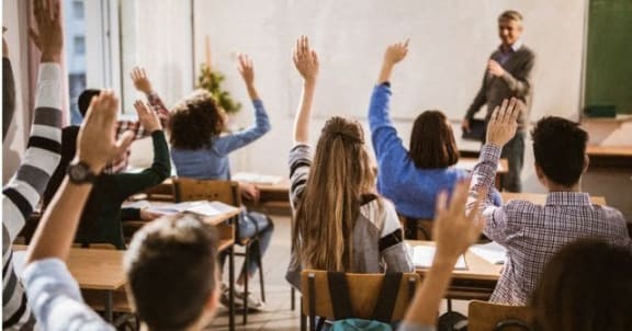 a group of students with their hands up in a classroom