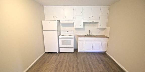 A kitchen area with a white fridge, stove, and cabinets.