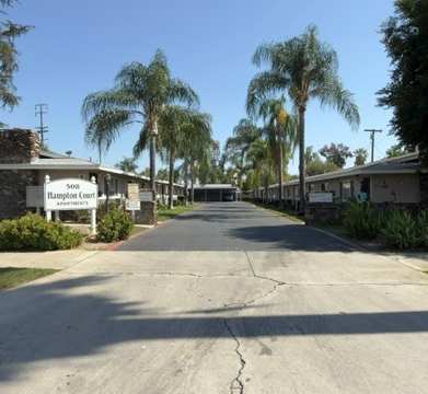A street view of a residential area with houses and palm trees.