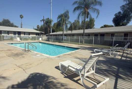 A pool with a sun lounger in front of a building.