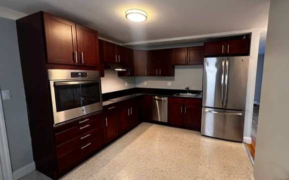 A kitchen with dark wood cabinets and stainless steel appliances.