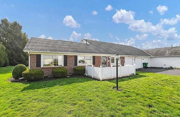 a brick house with a yard and a white fence