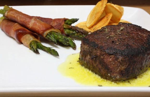 a plate of food with steak and asparagus and fries