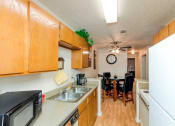 Thumbnail 4 of 18 - Kitchen with Hardwood-Style Flooring, Wood Cabinetry, White Appliances, and Double Sink