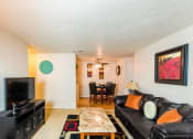 Thumbnail 8 of 18 - Spacious Model Apartment Living Room with Seating, Coffee Table, Entertainment Console, and Dining Room with Dining Table