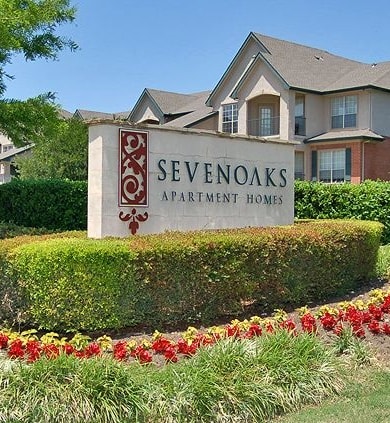 a sign in the grass in front of a house  at Seven Oaks Apts, Garland, TX