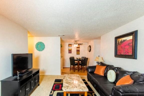 Spacious Model Apartment Living Room with Seating, Coffee Table, Entertainment Console, and Dining Room with Dining Table