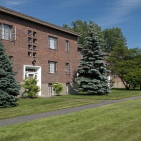 a large brick building with trees and grass in front of it