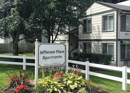 A sign for Jefferson Place Apartments is in front of a building.
