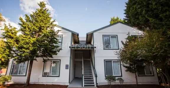 A white two-story house with a staircase leading to the entrance.