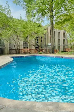 A small pool in a backyard with a house in the background.