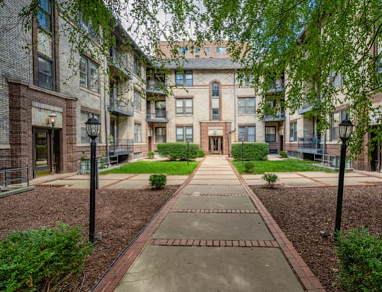A courtyard with a brick pathway and a building in the background.