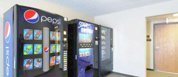 A Pepsi vending machine sits in a room with a door to the right.