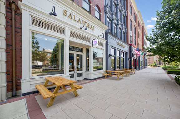 a sidewalk with picnic tables outside of a building