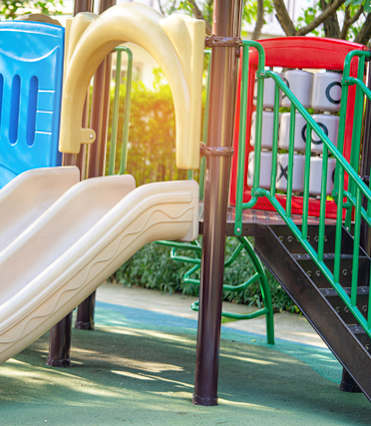 A playground with a blue slide and a red and green structure.