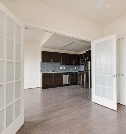 an empty living room with a kitchen in the background