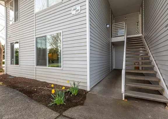 A house with a grey siding exterior and a staircase leading to the entrance.
