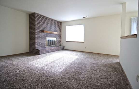 A room with a brick fireplace and a window.