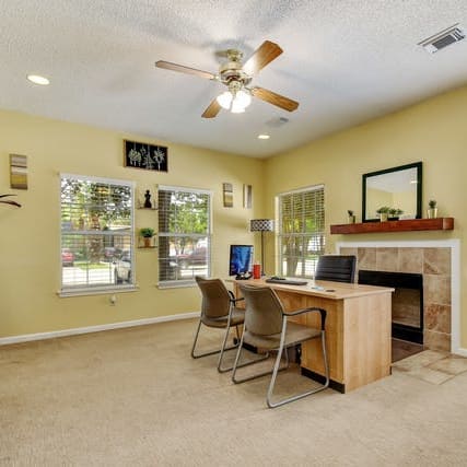 a room with a fireplace and a desk with chairs at Regency Village in San Antonio