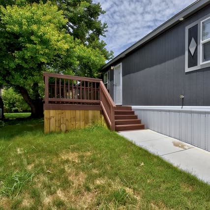 a house with a wooden deck in a yard at Regency Village in San Antonio