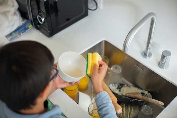A person is washing dishes in a kitchen sink.