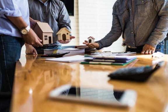 three men are working on a table with miniature houses