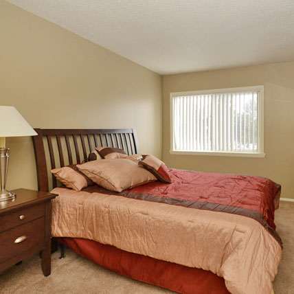A bedroom with a bed, nightstand, and dresser.