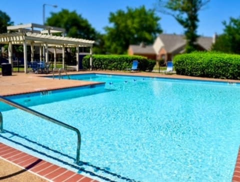 a large swimming pool with a pavilion and trees in the background