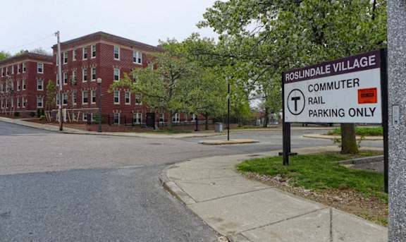 A sign in front of a building that says Roslindale Village and Commuter Rail Parking Only at Conway Court, Roslindale, 02131