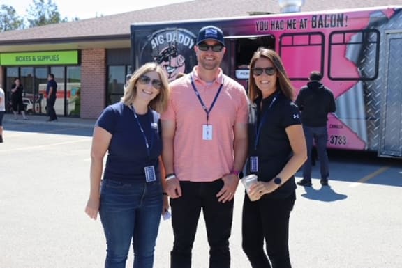 a man and two women standing in front of a food truck